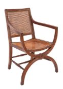 A 19th Century oak curule armchair after a design by Thomas Hope having a cane panel back and seat,