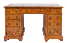 An Edwardian oak pedestal desk in the Gothic manner, the rectangular top with a bevelled edge,