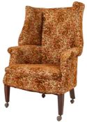 An upholstered wing back armchair in George II style,