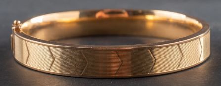 A hinged bangle, decorated with chevron pattern, stamped '750', inner diameter ca.