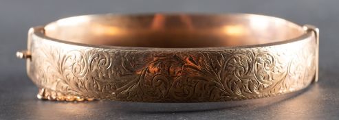 A 9ct gold hinged bangle, with foliate engraving, inner diameter ca. 6cm, total weight ca. 16gms.