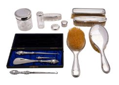 A George V matched silver dressing table set; comprising a pair of silver backed brushes,