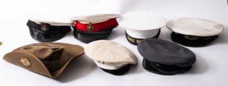 A collection of military headdress, including a Royal Marine's peaked cap, a Royal Navy peaked cap,