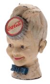 A Coca-Cola cast iron money box in the form of a boy with bottle top to forehead, 19cm high.