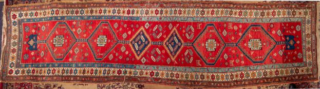 A Caucasian runner, the red field with a row of serrated lozenge and hexagonal medallions,