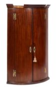A George III mahogany bow fronted hanging corner cupboard,