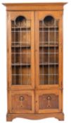 An Arts & Crafts oak and inlaid bookcase; with a moulded cornice,