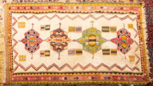 A Persian Kelim, the ivory field with four geometric medallions in wine,