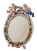 A German porcelain easel mirror in the Meissen manner applied with cherubs and flowers,