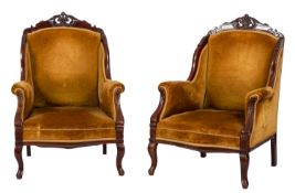 A pair of Edwardian carved mahogany semi-wing frame armchairs,