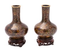 A pair of small Chinese cloisonné bottle vases decorated overall with flowers and foliage on a dark