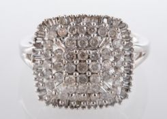 A diamond cluster ring, the cushion shaped plaque claw-set with circular and baguette cut diamonds,