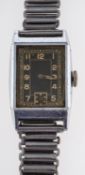 An early 20th century chrome tank-style wristwatch the black rectangular dial with arabic numerals