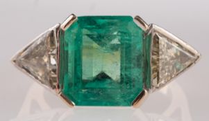 An 18ct gold, emerald and diamond three-stone ring, the square cut emerald, stated to weigh 5.