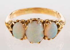 A three stone opal ring, set with three oval cabochon opals in claw settings,