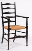 An Edwardian ebonised ash ladderback elbow chair, with ball-shaped finials,