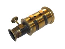 A lacquered brass projection lens with manual adjusters, unsigned, 16cm long, .