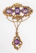 A Victorian amethyst brooch, circa 1870, the openwork scrolled brooch with engraved foliate detail