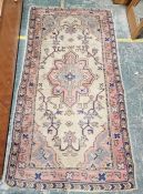 Modern wool pile pink ground rug with central floral medallion on a floral field with spandrels,