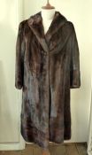 A full length dark mink coat, shawl collar, hook and eye fastening, the hem and cuffs banded
