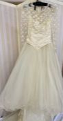 A cream wedding dress with train, lace over a fitted bodice lace full length sleeves,  ruched