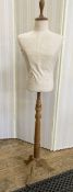 Modern dress mannequin of half-torso, on adjustable wooden tripod stand, with a label attached '