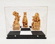 Three contemporary Chess Piece dragons on painted square stand in Perspex box, 17cm wide x 13.5cm
