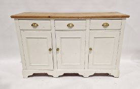Cream painted pine low dresser with plain boarded top, three frieze drawers and cupboards below,