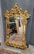 Reproduction gilt wall mirror with ornate pierced floral foliate scroll pediment, scroll borders and