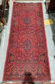 Eastern red ground rug with two central geometric medallions on floral field, multiple floral and