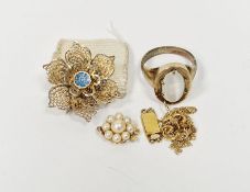 Gold coloured ring with moonstone chatoyancy, a gold coloured flower shaped brooch with blue