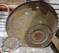 Three brass Asian trays, each circular, having embossed and engraved decoration, one of which having