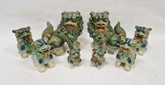 Collection of eight pottery Chinese-style models of dogs of fo, each glazed in mottled green,