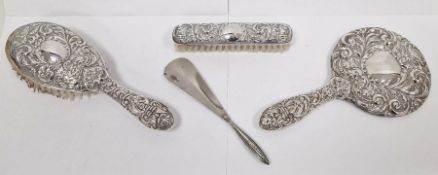 Three-piece silver-mounted dressing set comprising of two brushes and a mirror, repousse