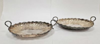 Pair of Victorian silver two-handled oval dishes, leaf and scroll engraving, each on four bun