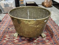 Circular copper log basket with rolled rim supported on three lions paw feet, 36cm high x 58cm