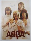 Signed ABBA publicity card featuring a photograph of all four members of the band, signed by each.