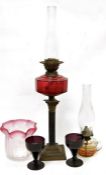 Victorian brass and cranberry glass oil lamp having panelled glass oil well, on corinthian column