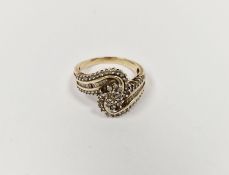 Gold-coloured metal and white stone dress ring, scroll design (some stones missing)