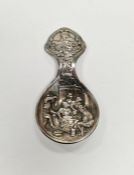 Continental white metal tea caddy spoon with embossed deoration depicting a traditional 19th century