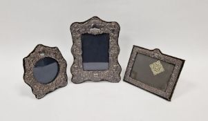 Three Victorian-style silver photograph frames, the largest of scroll outline form cast with putti