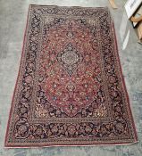 Persian style red ground rug with central floral medallion on floral field and floral spandrels,