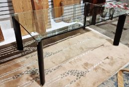 Large glass-topped coffee table of rounded rectangular form raised on four black and metel legs,