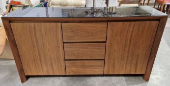 Contemporary teak sideboard with black glass top, three central drawers flanked by cupboards with
