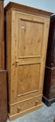A contemporary pine single door wardrobe over a single long drawer, measuring approx. 183 cm high