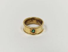Gold coloured metal and emerald coloured stone ring, the wide band set with single green stone and