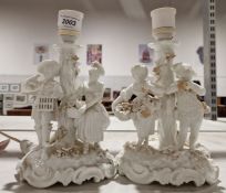 Pair of white glazed pottery table lamps with male and female figure group, with crossed sword