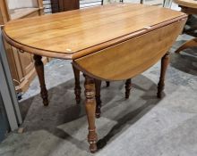 Modern stained wood extending dining table, oval, on turned supports with six extending leaves,