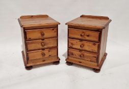Pair of modern pine three-drawer bedside chests of drawers with turned knob handles and bun feet,
