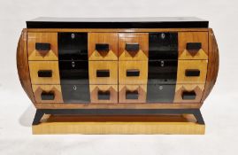 A French Art Deco walnut veneered and black painted chest of drawers, of bombe shape with two